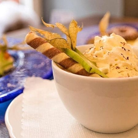 Nachspeise mit Sahne, Sternfrucht und Keksröllchen garniert.