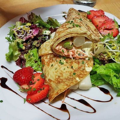 Pfannkuchen gefüllt mit Spargel und Salat und Erdbeeren als Beilage.